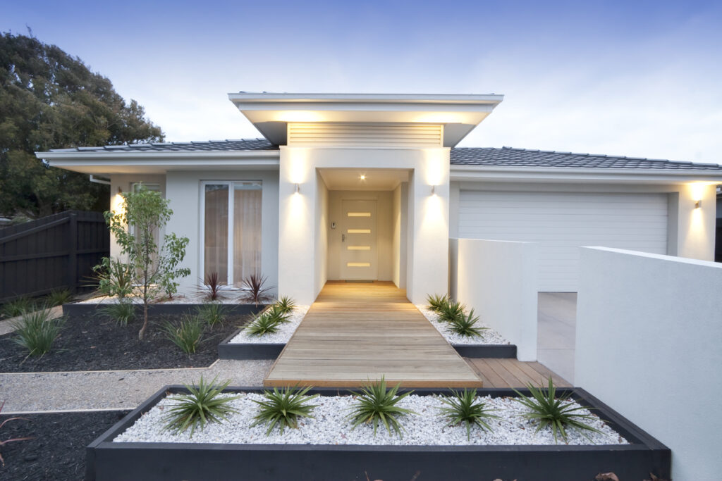 A photo of a modern Australian house at dusk with the outside lights on.